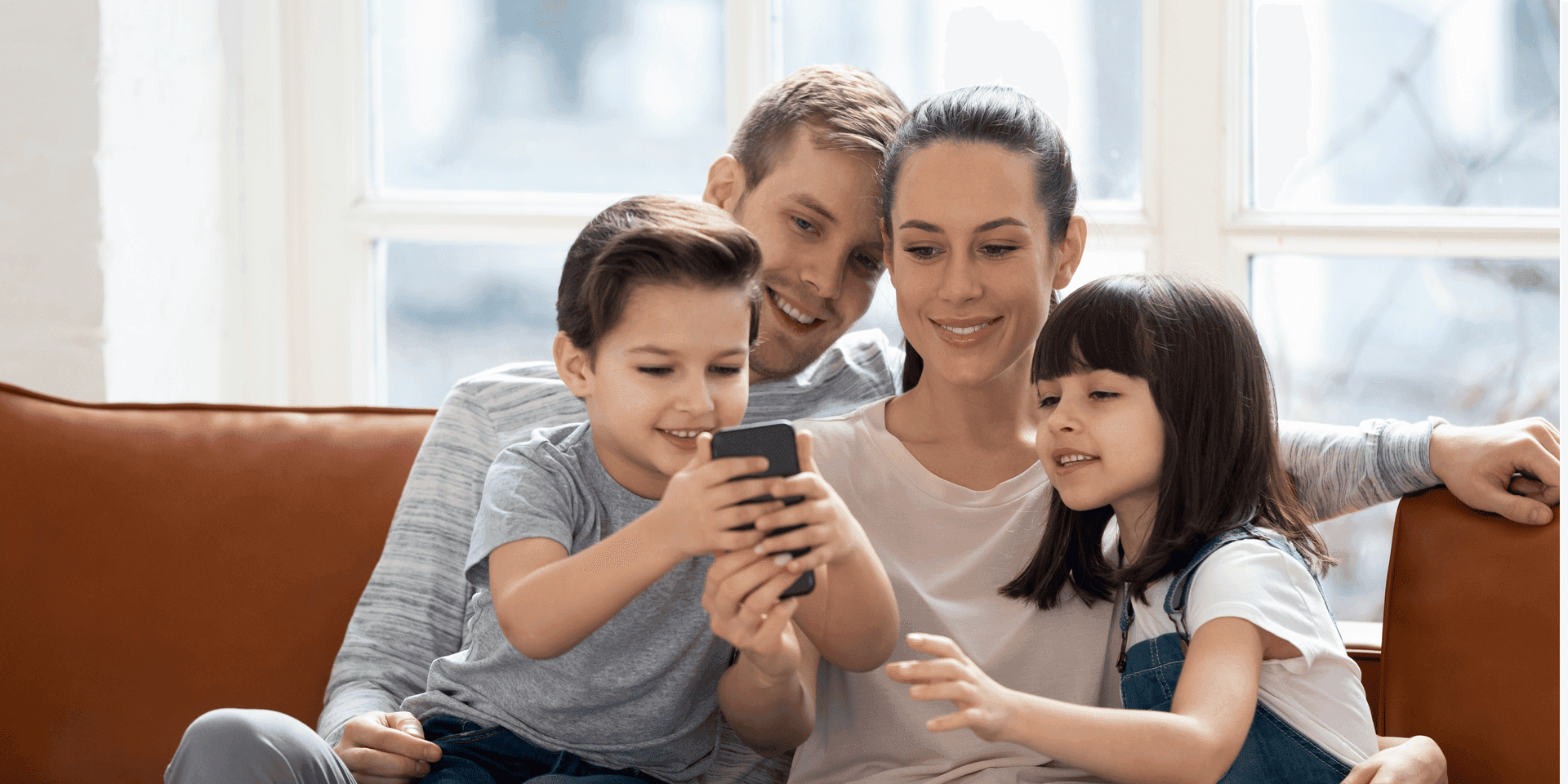Family on sofa looking at a phone together