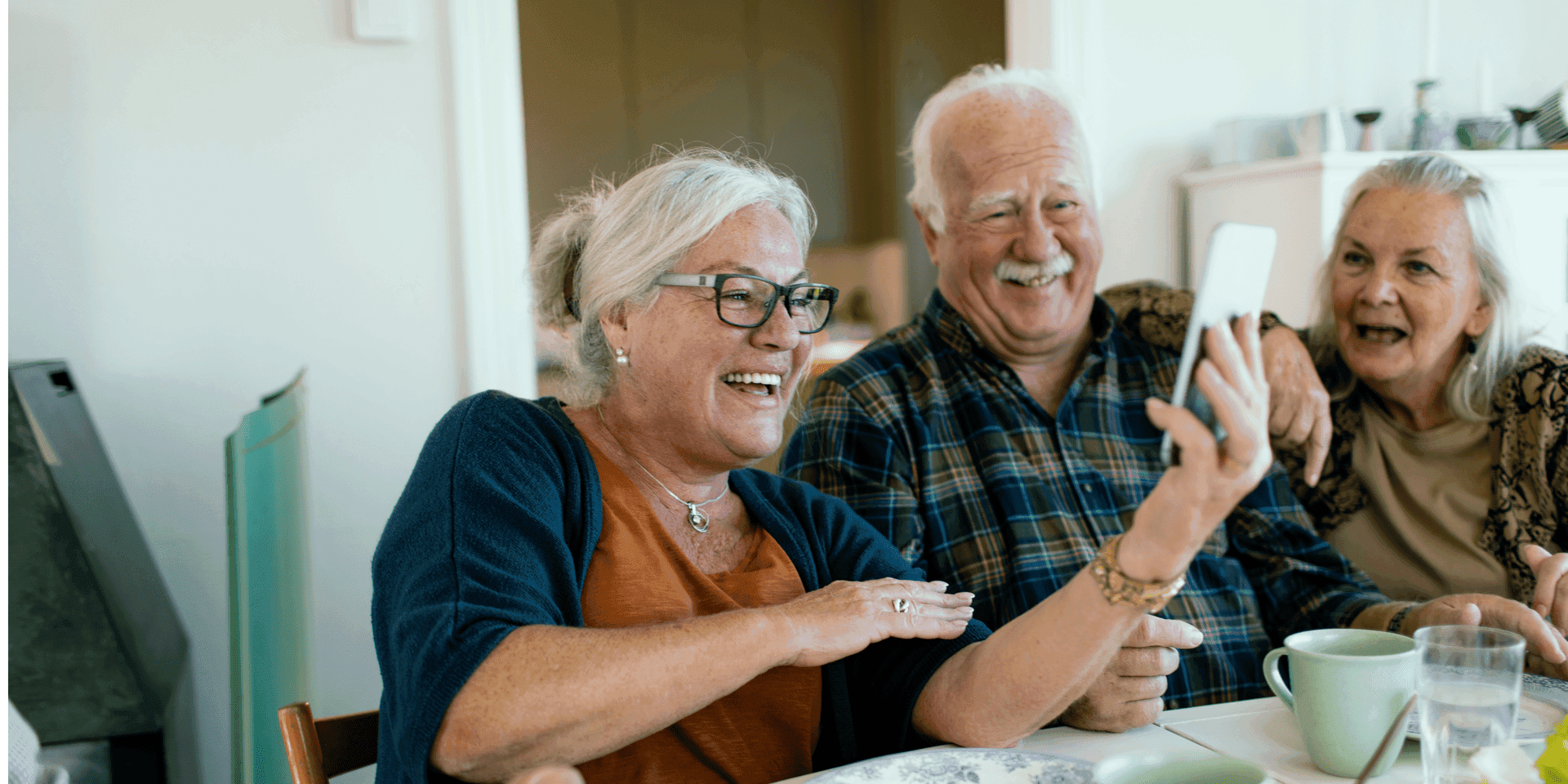 Two smiling senior friends looking at a mobile phone together outdoors